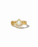 Gold ring with a central opal stone and smaller diamonds on a white background
