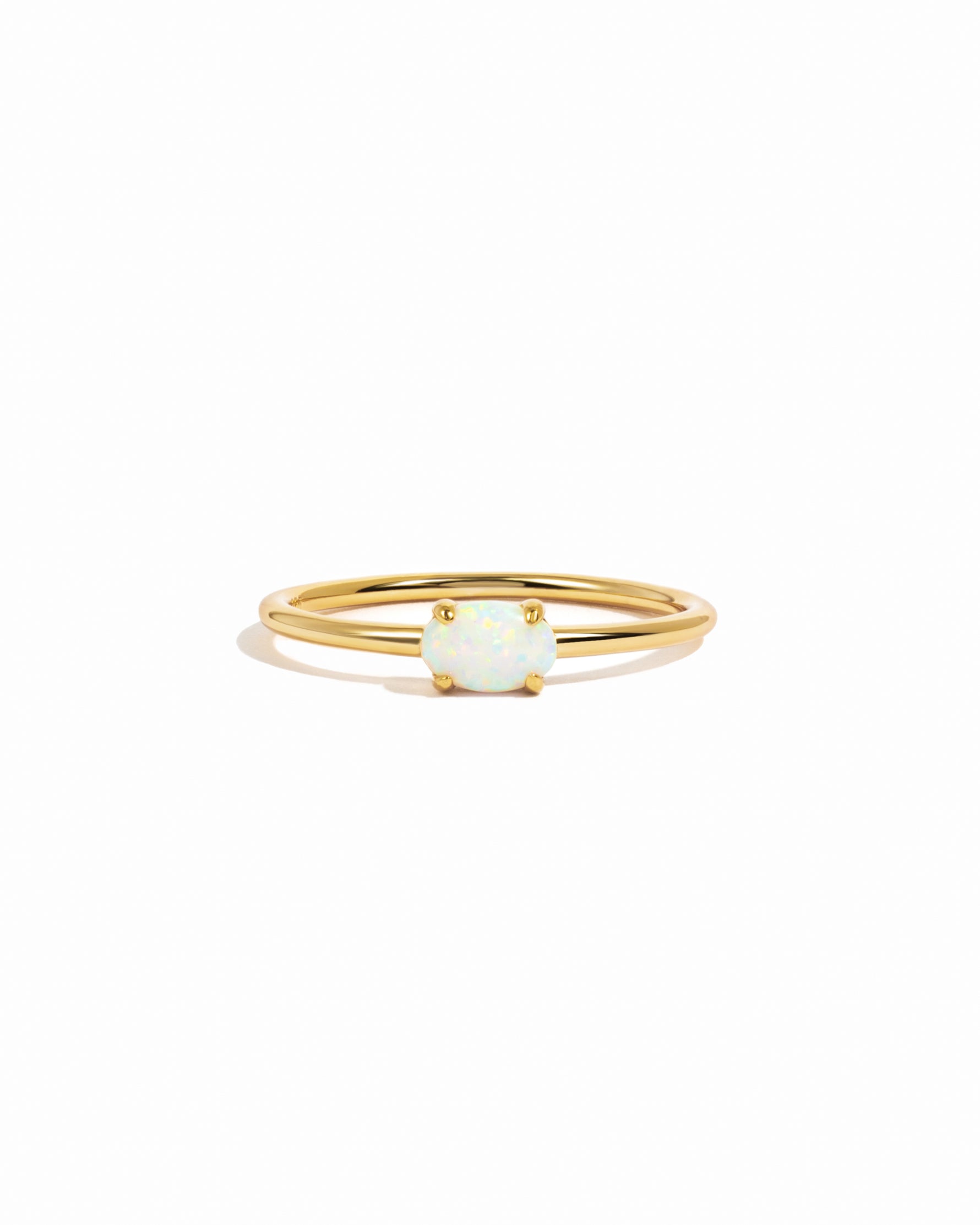 Gold ring with a white opal solitaire stone on a white background