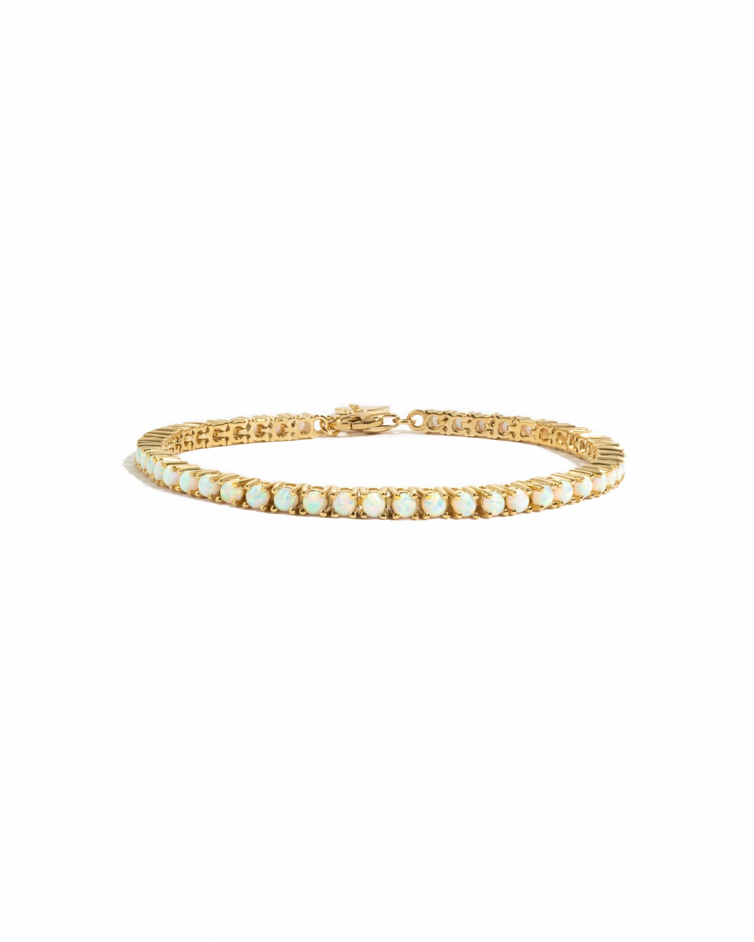 A tennis style opal bracelet with gold plating and a lobster clasp closure, displayed on a marble surface.