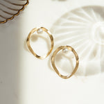 closeup image of modern earrings featuring a gold statement earring with freshwater pearl