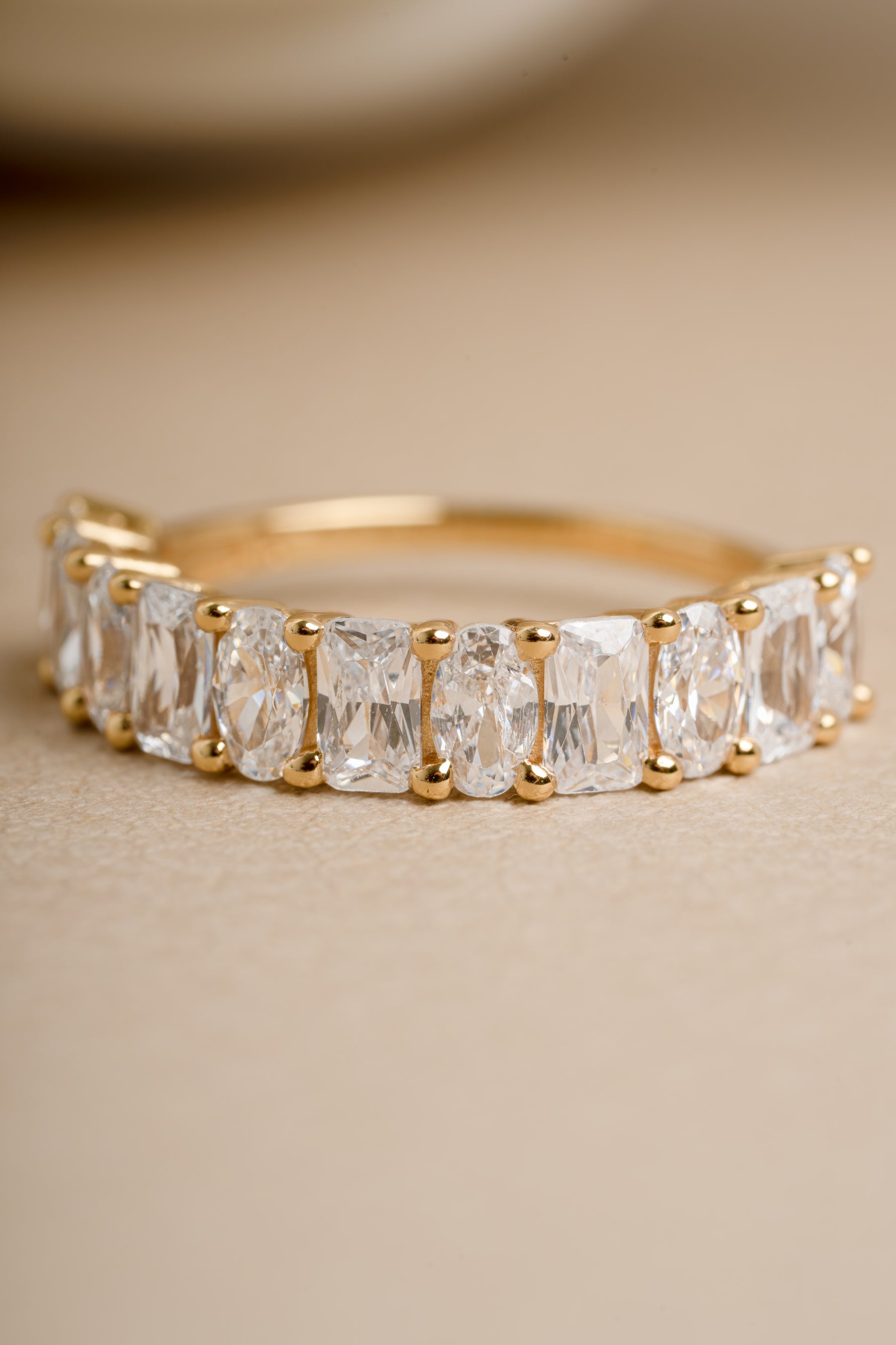 Gold oval cut and diamond cut ring for women on beige background