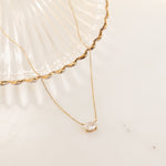 Flatlay image of gold necklace with oval solitaire diamond 