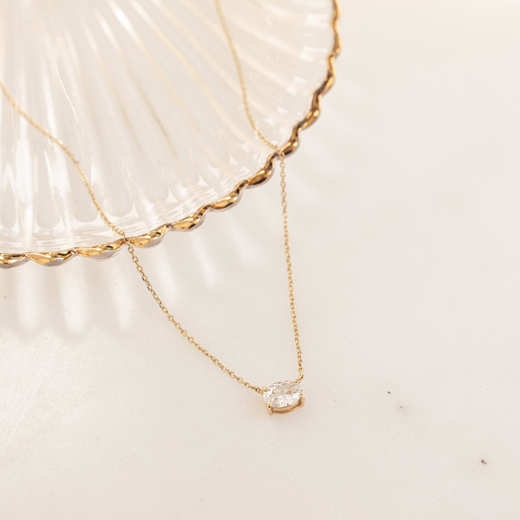 Flatlay image of gold necklace with oval solitaire diamond 