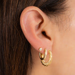 Gold hoop earring stack with a twisted hoop earring, a gold oval hoop, and a diamond stud earring