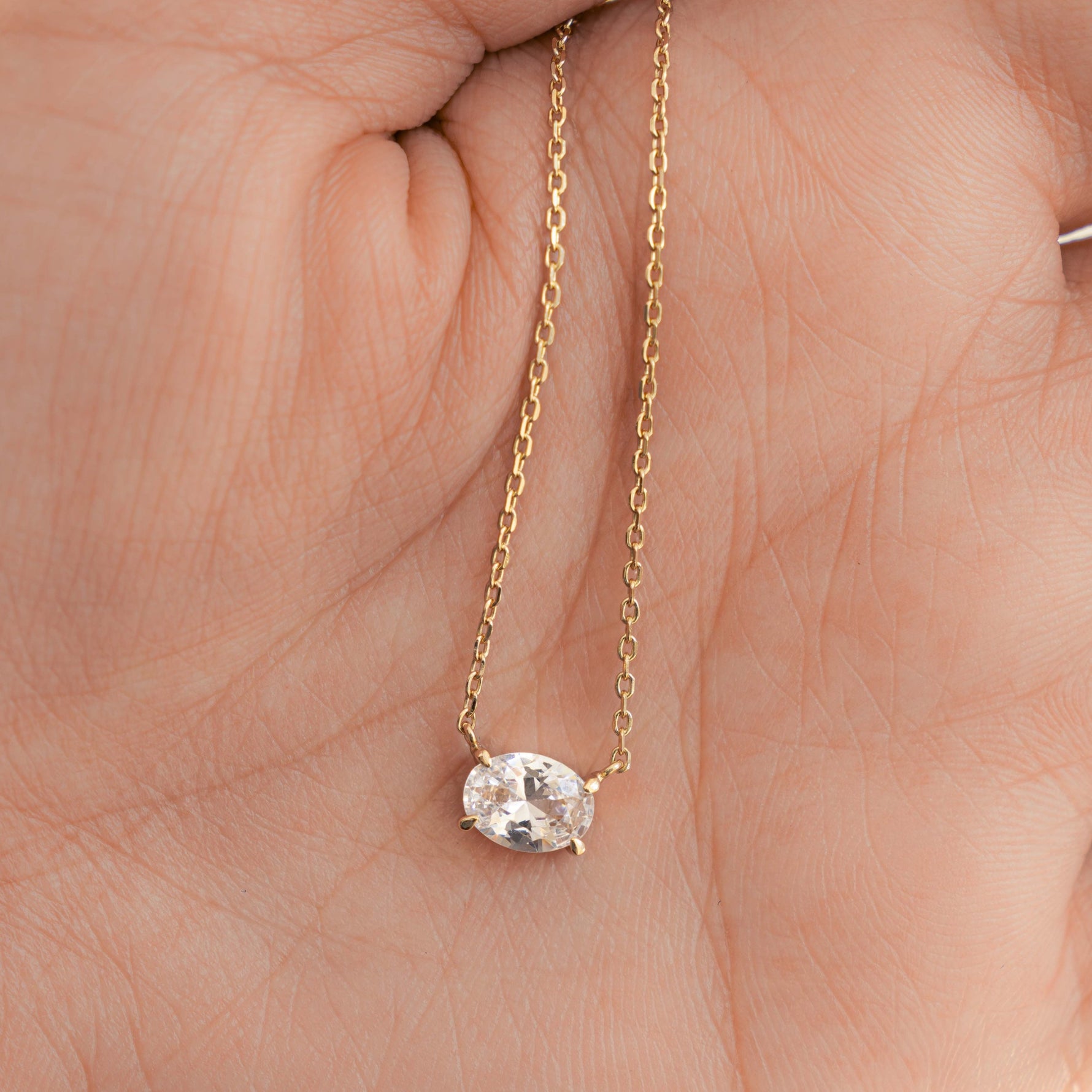 Model holding diamond necklace in gold