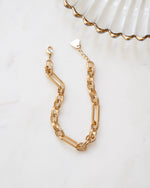 Gold paperclip statement bracelet with a chain link design on a plain background