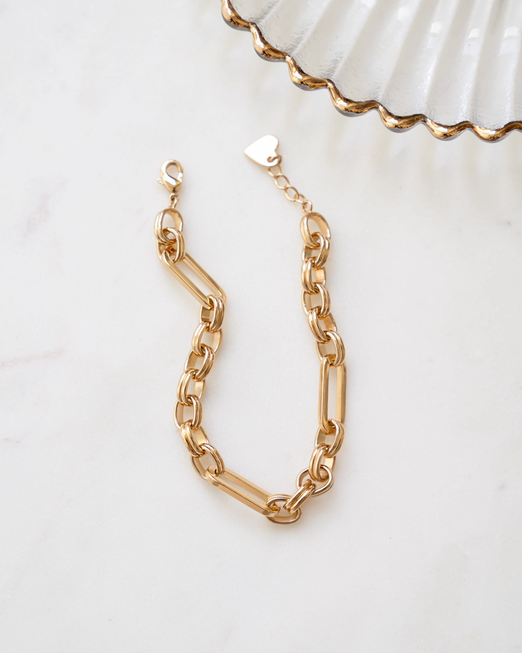 Gold paperclip statement bracelet with a chain link design on a plain background