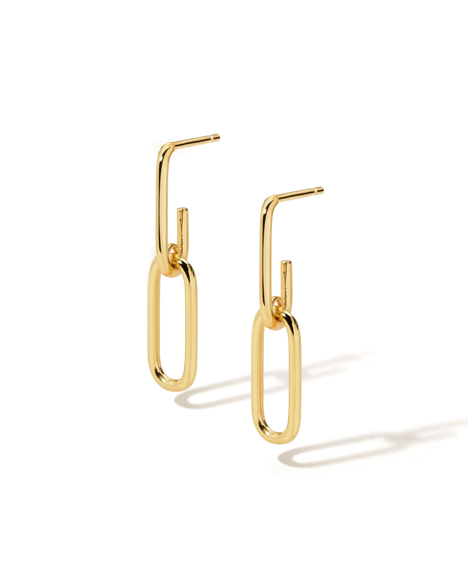 Gold paperclip dangle earrings on a white background