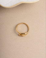 Gold cubic zirconia diamond ring on a beige surface