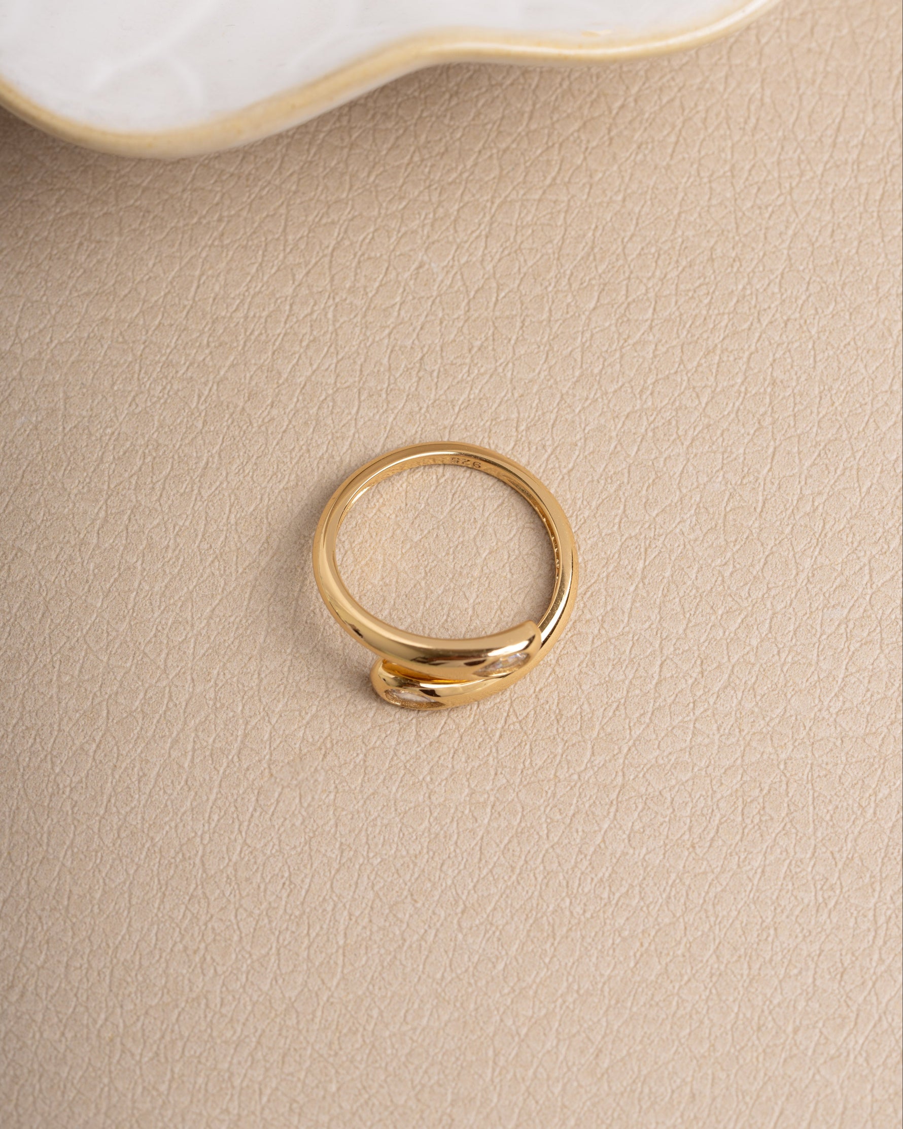 Gold cubic zirconia diamond ring on a beige surface