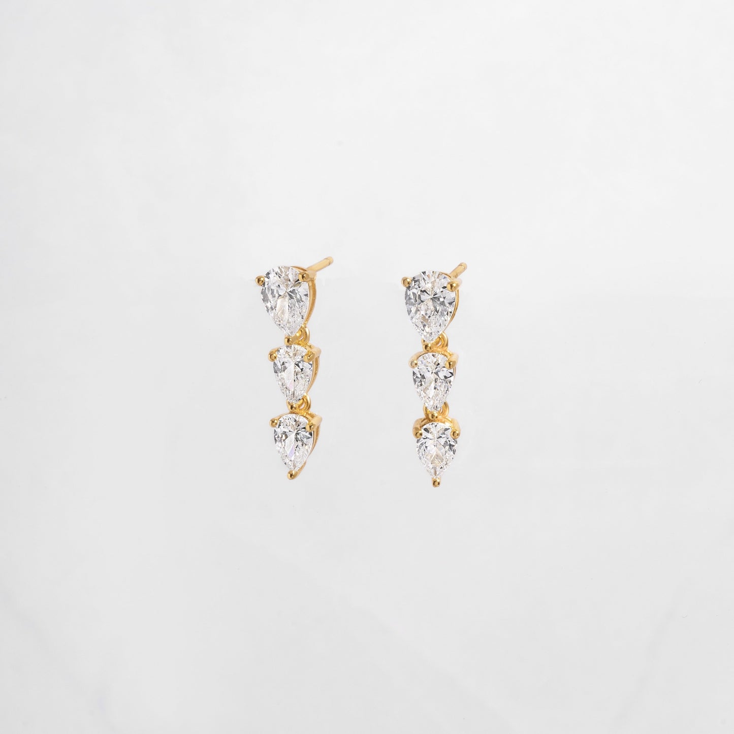 close up of cubic zirconia gemstone earrings with a pear drop shape set in gold. 