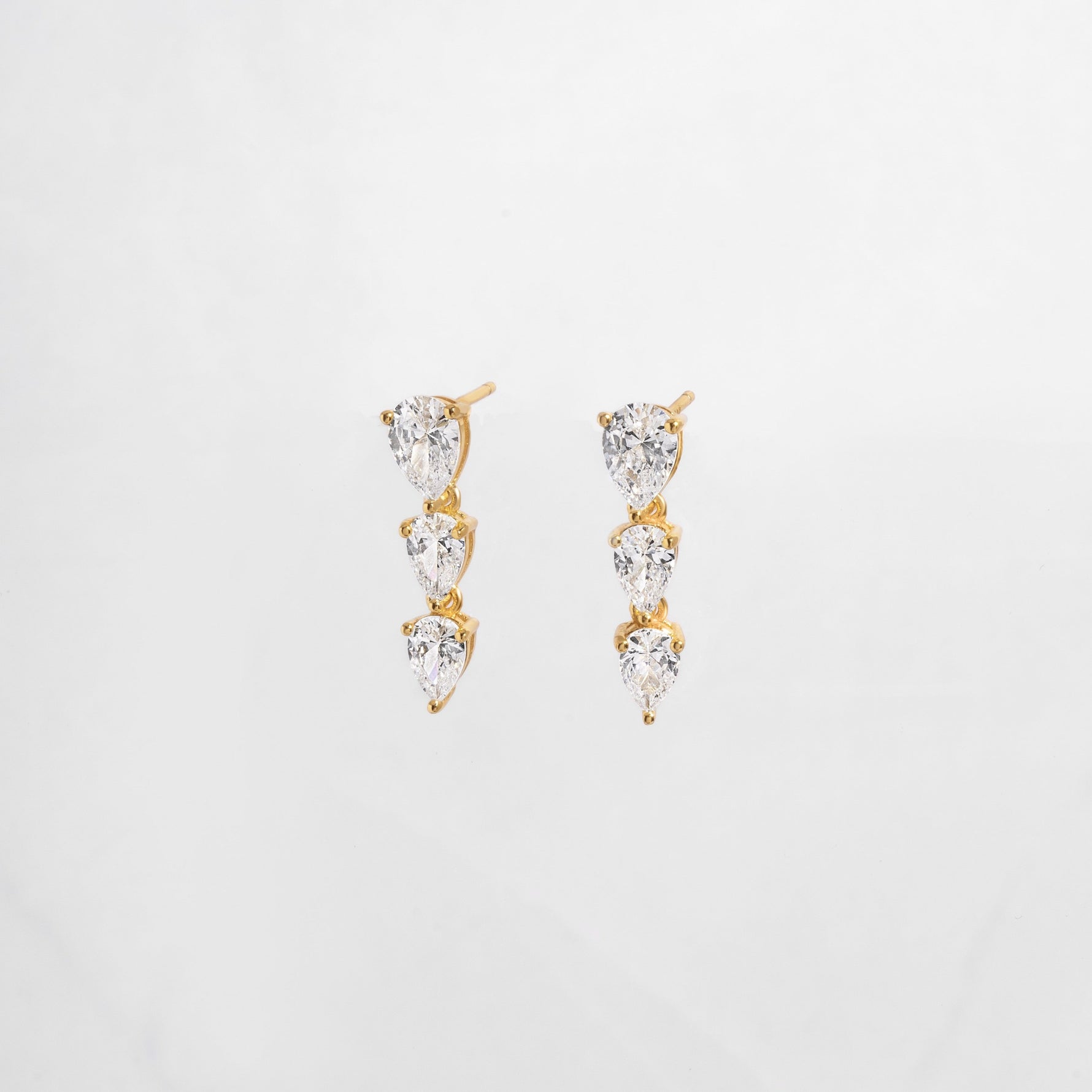 close up of cubic zirconia gemstone earrings with a pear drop shape set in gold. 