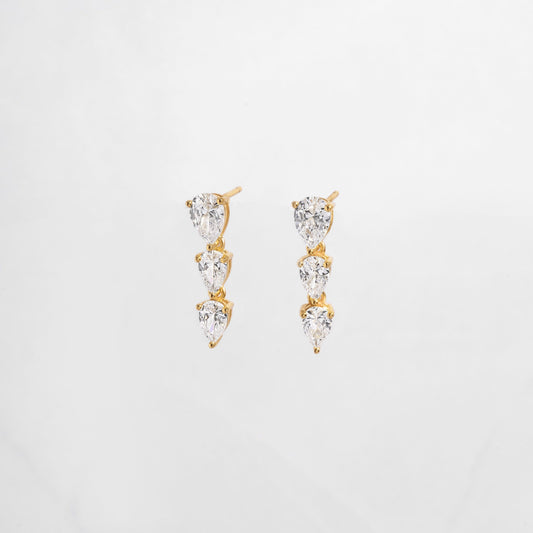 close up of cubic zirconia gemstone earrings with a pear drop shape set in gold. 