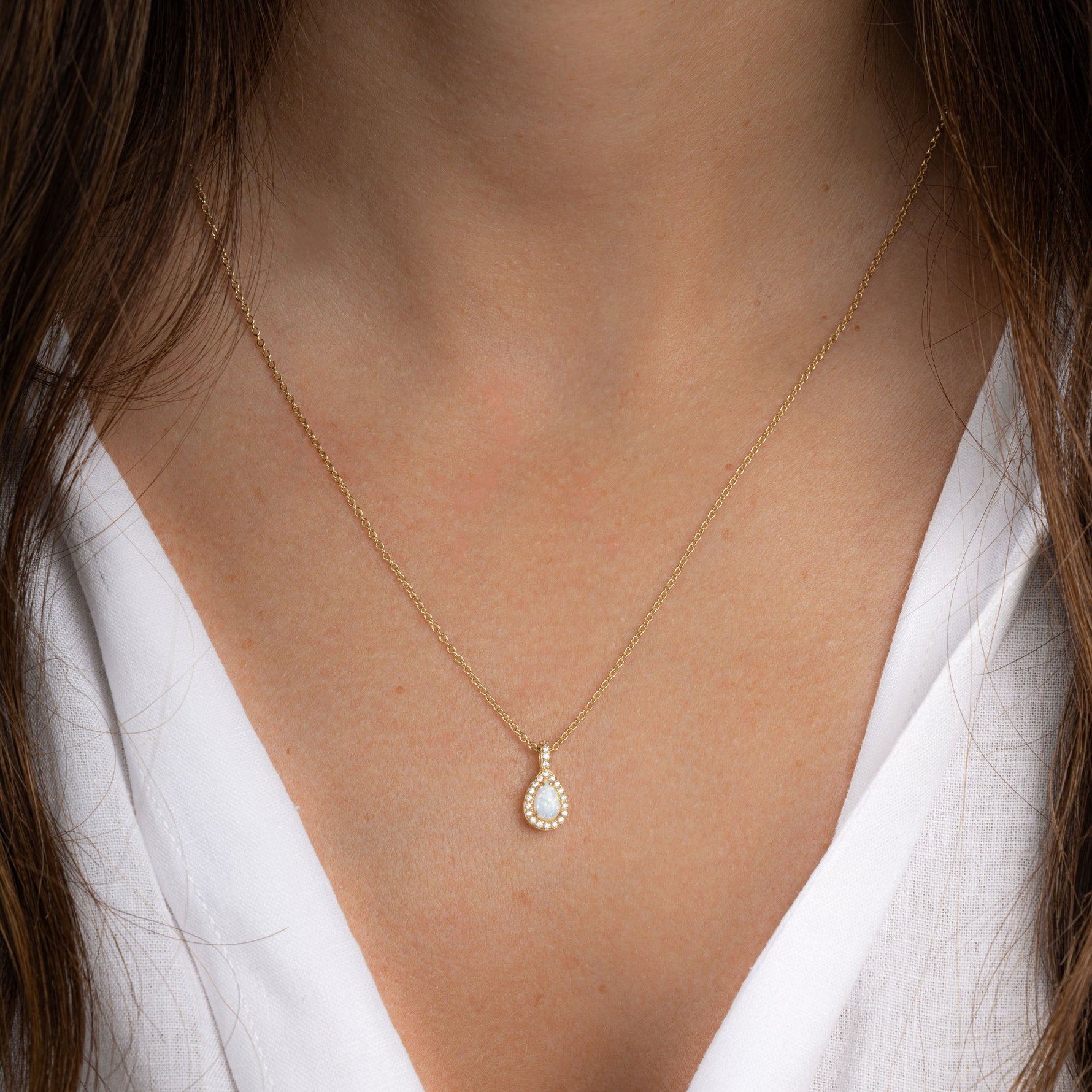 Model wearing birthstone necklace in opal with 14k gold plating