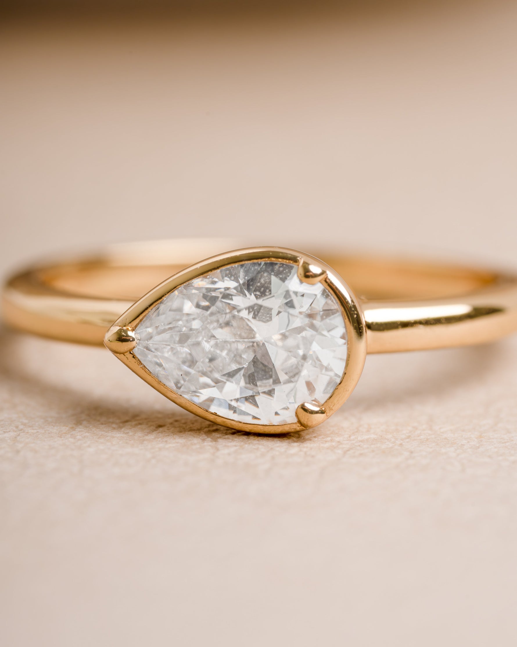 Gold ring for women with a pear cut solitaire stone on a blurred background