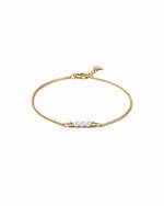Gold bracelet with three pearls on a white background