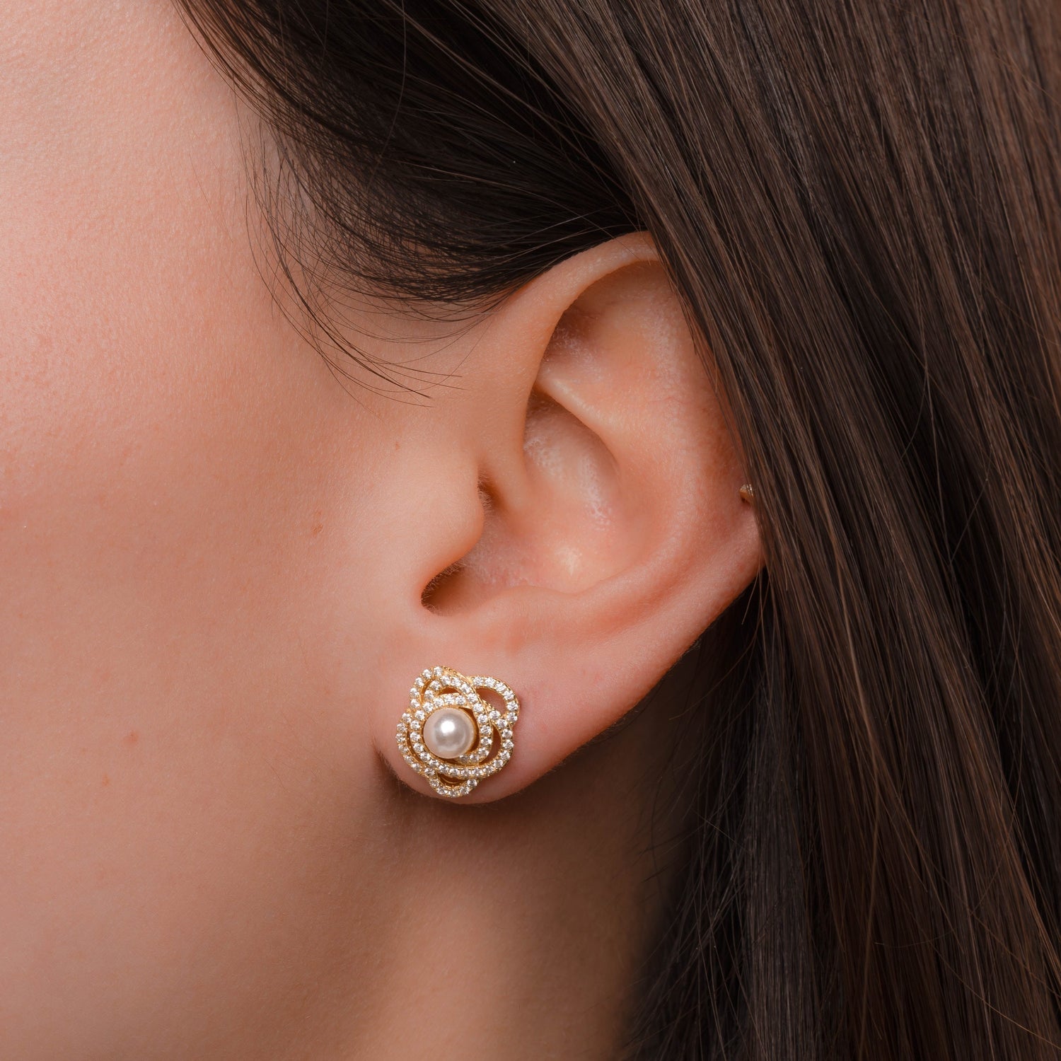 Model wearing gold stud earrings with floral earring design, cubic zirconia diamonds, and pearl earring design