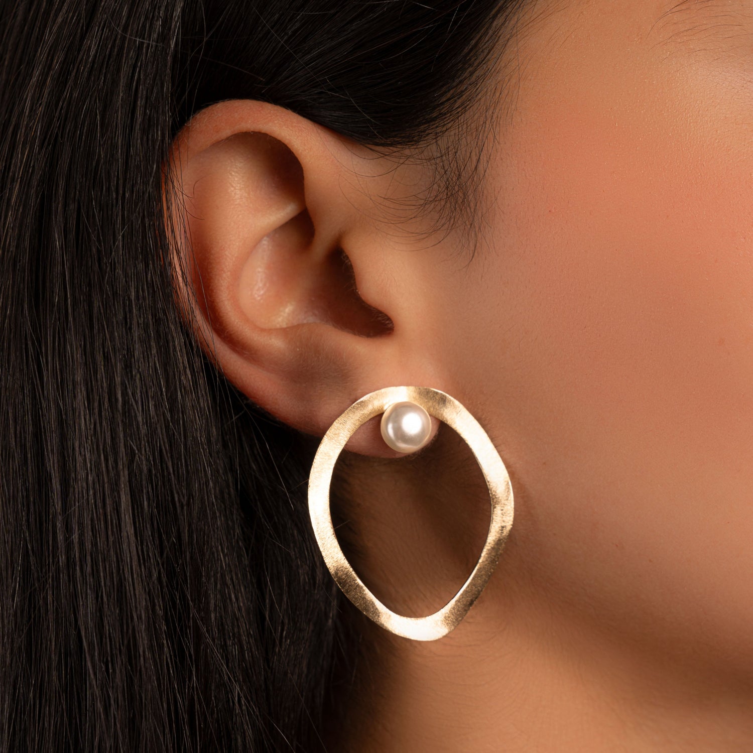 model wearing a unique earring featuring a pearl statement earring with an organic shape 