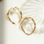 closeup image of gold asymmetric earrings with a freshwater pearl