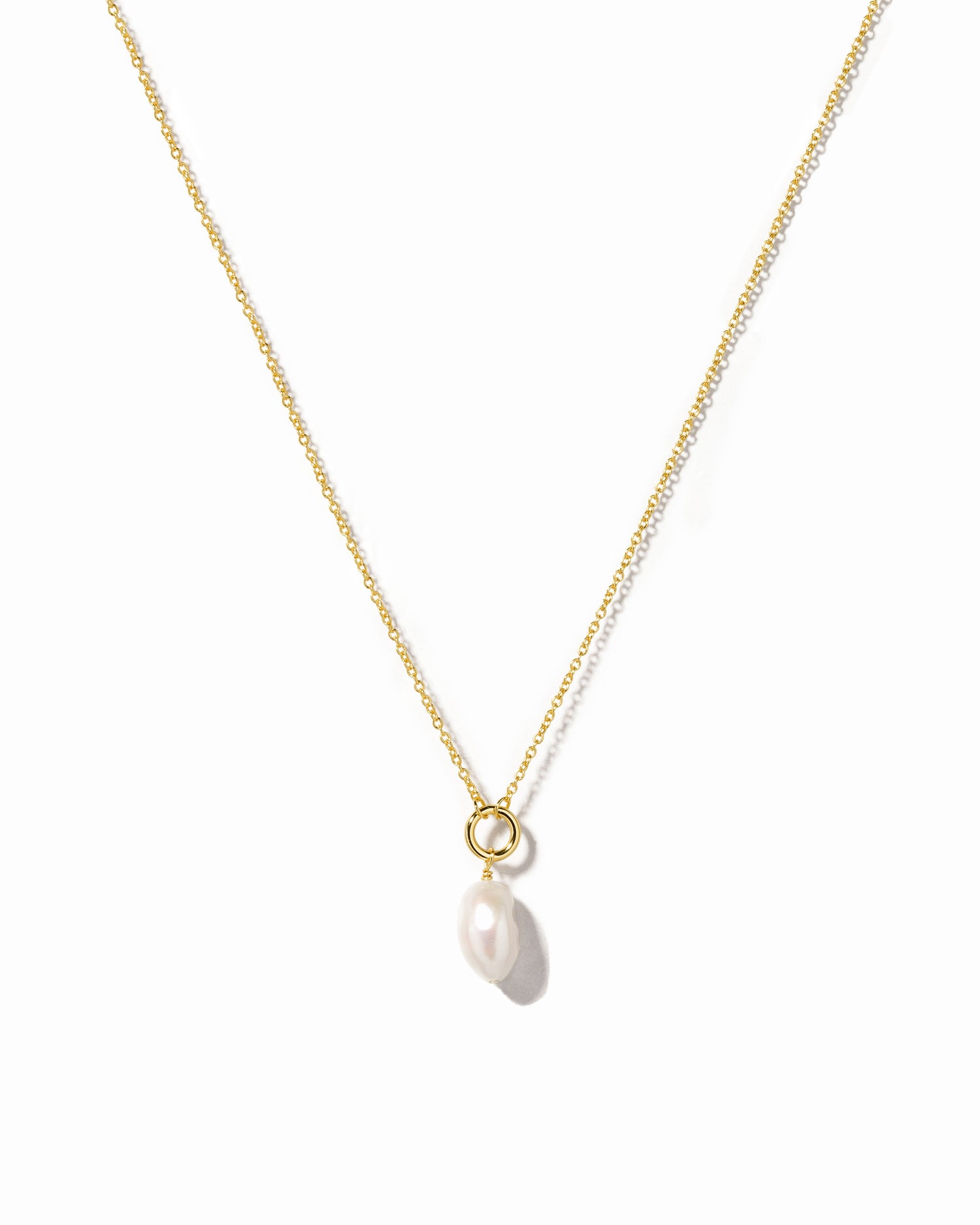 Gold necklace with a single pearl pendant on a white background