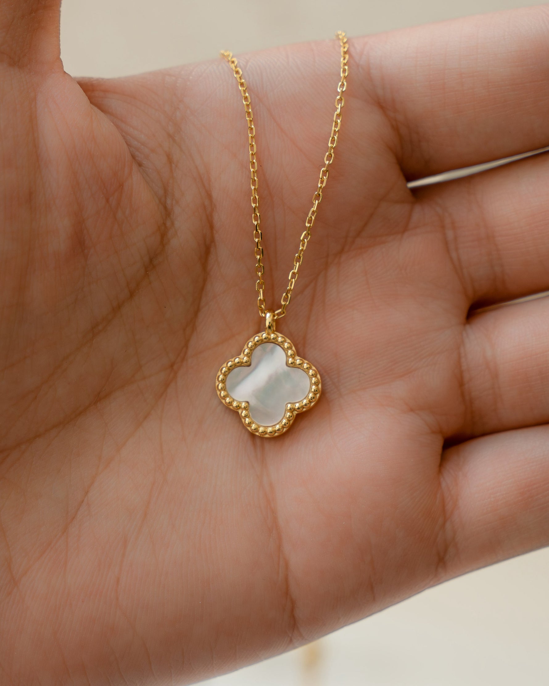 gold pendant necklace with a mother of pearl four leaf lucky clover pendant