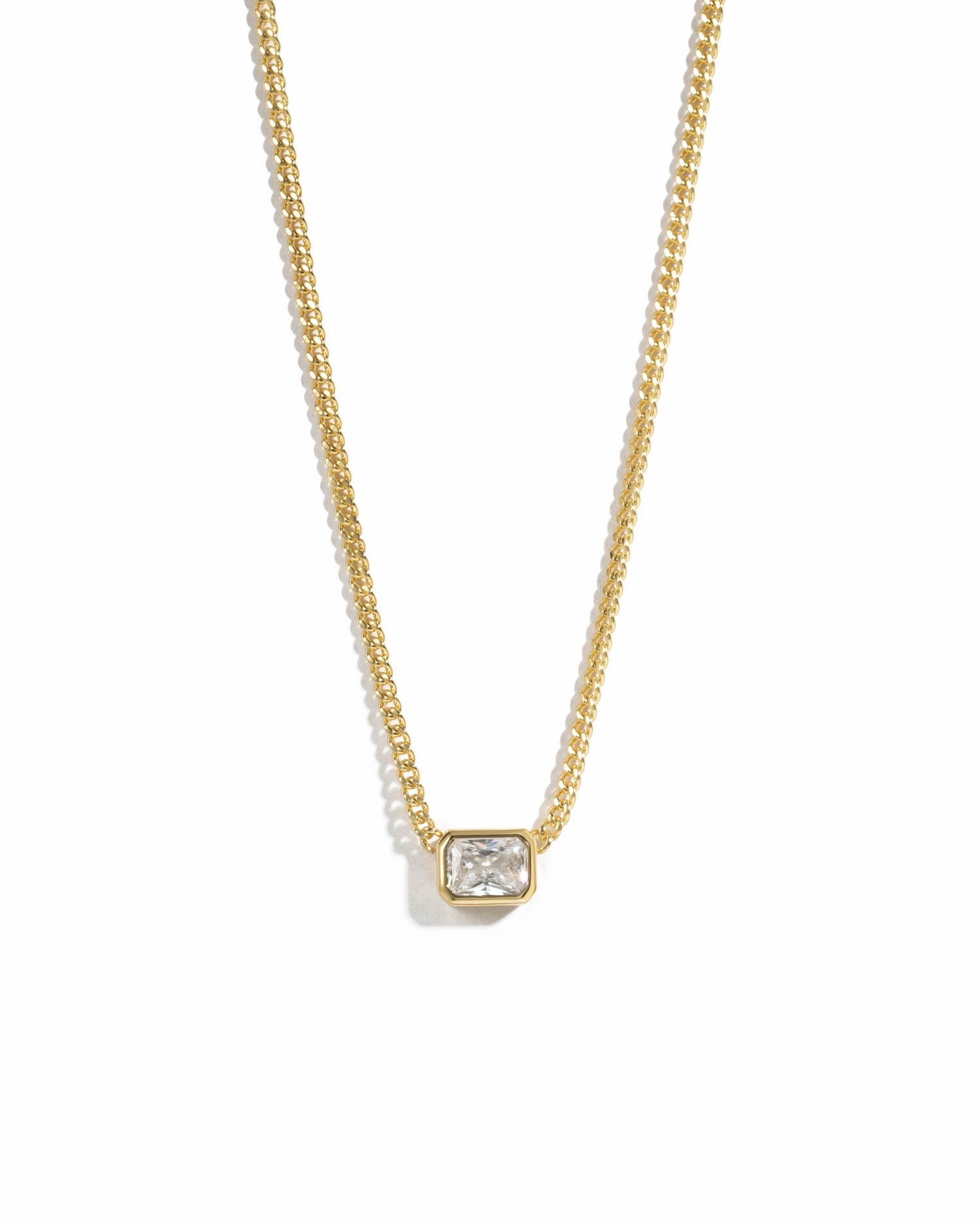 Gold necklace with a rectangle diamond pendant on a white background