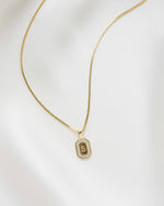 Gold diamond necklace with a custom diamond pendant of an "S" initial on a white background