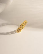 Gold chain ring on a light beige surface