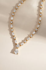 Gold teardrop diamond pendant dainty necklace on a white background