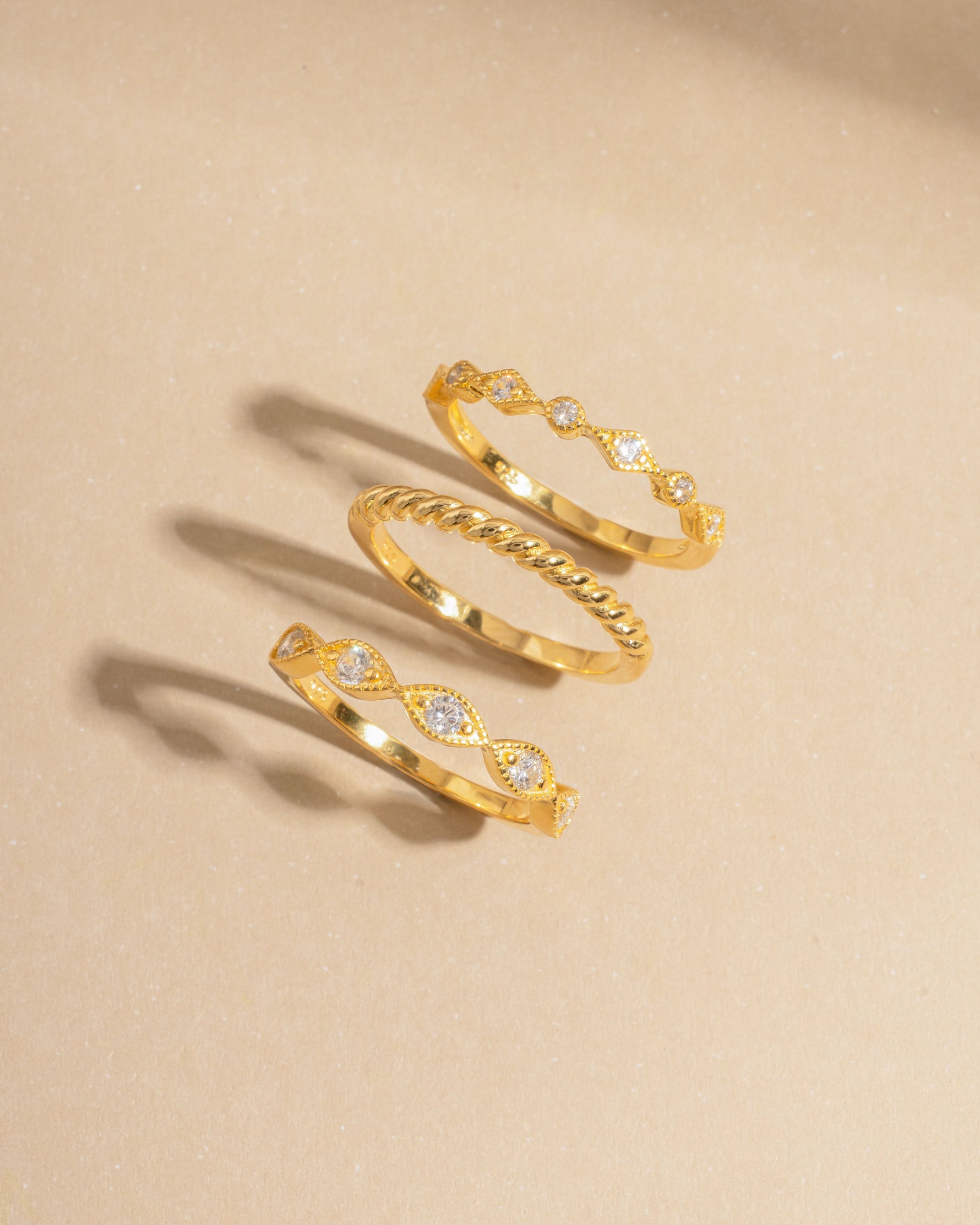 Stacking gold rings on a beige background