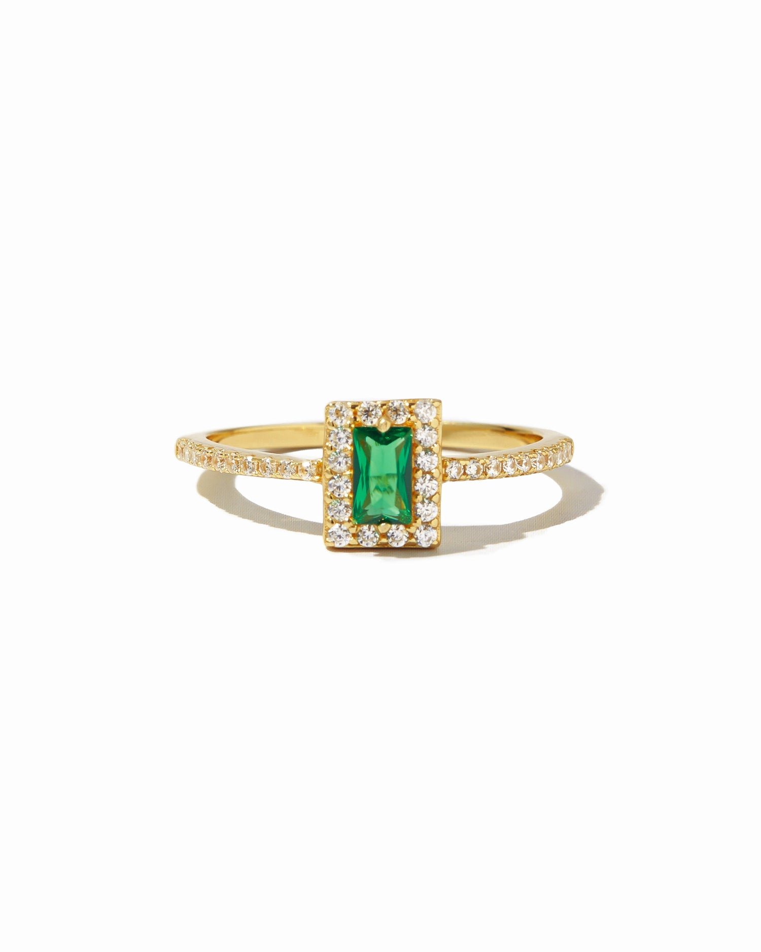 Gold ring with a emerald green gemstone on a white background