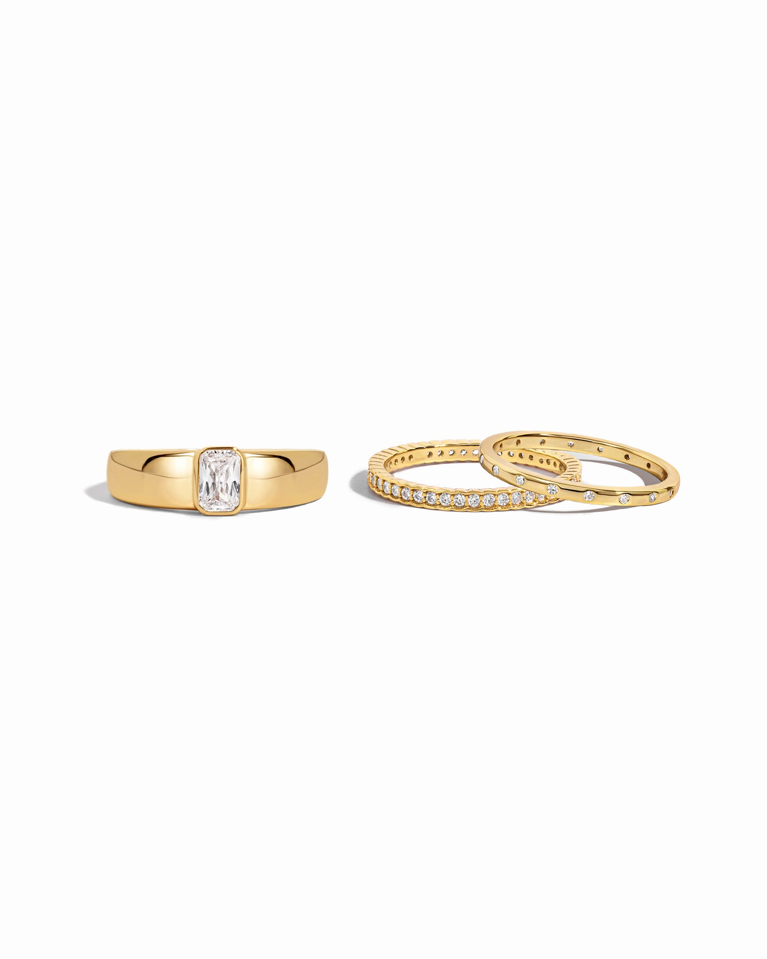 Gold dome ring with baguette stone and a dainty stacking ring set on a white background