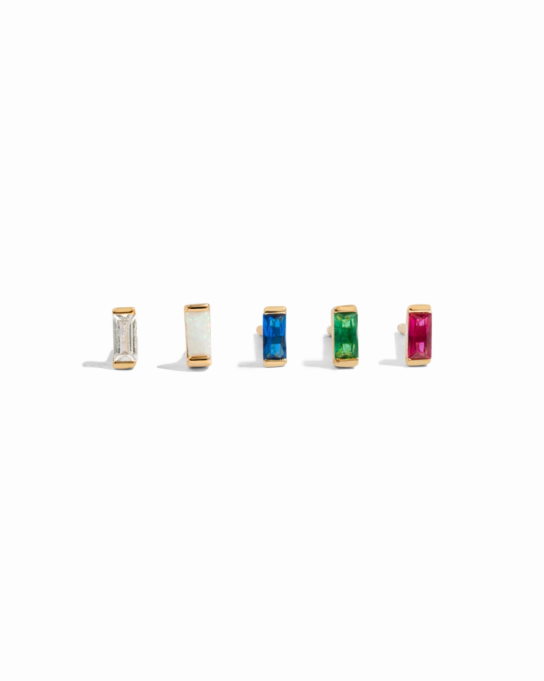 Set of five gold stud earrings with different colored birthstones on a white background featuring, white cz, opal, sapphire, emerald and ruby