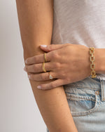 models wearing gold bracelets and a ring on a plain background