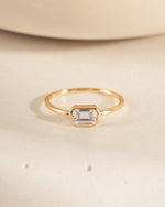 14k gold plated ring with a baguette cz stone on a beige background