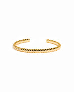 Gold spiral cuff bracelet on a white background