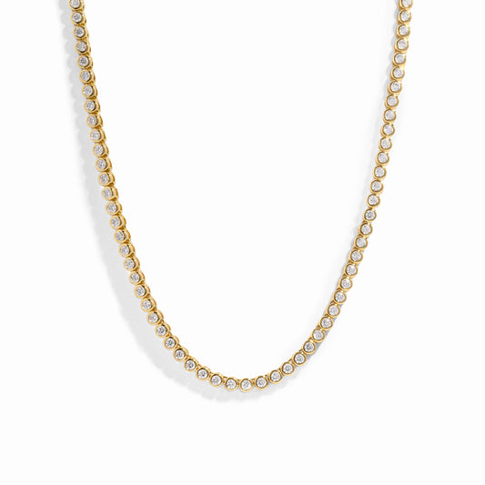gold tennis necklace with bezel-set stones on a white background