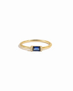 Gold ring with a sapphire gemstone on a white background