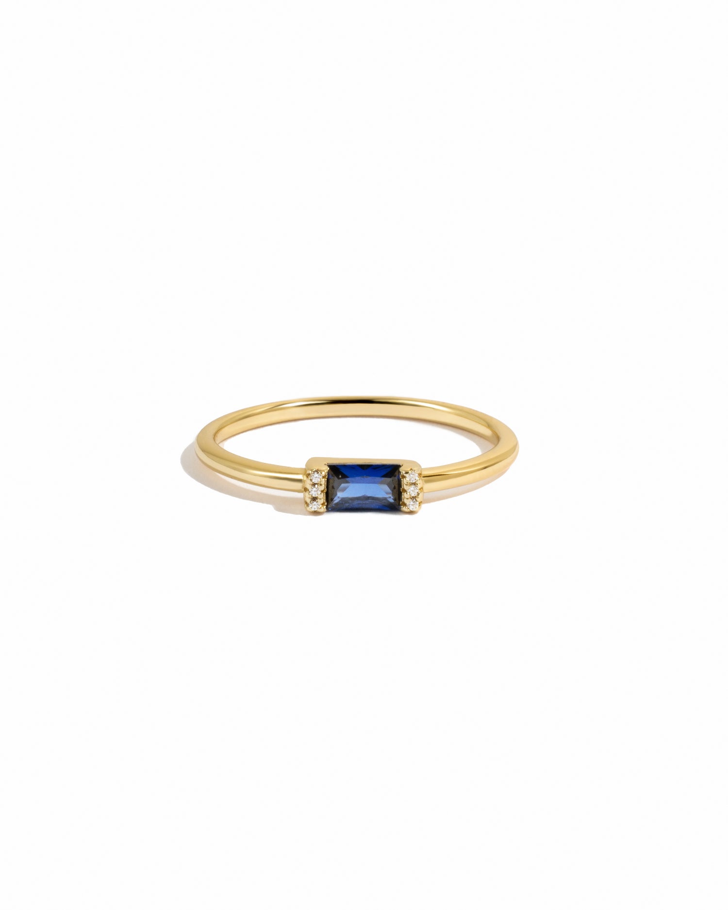 Gold ring with a sapphire gemstone on a white background