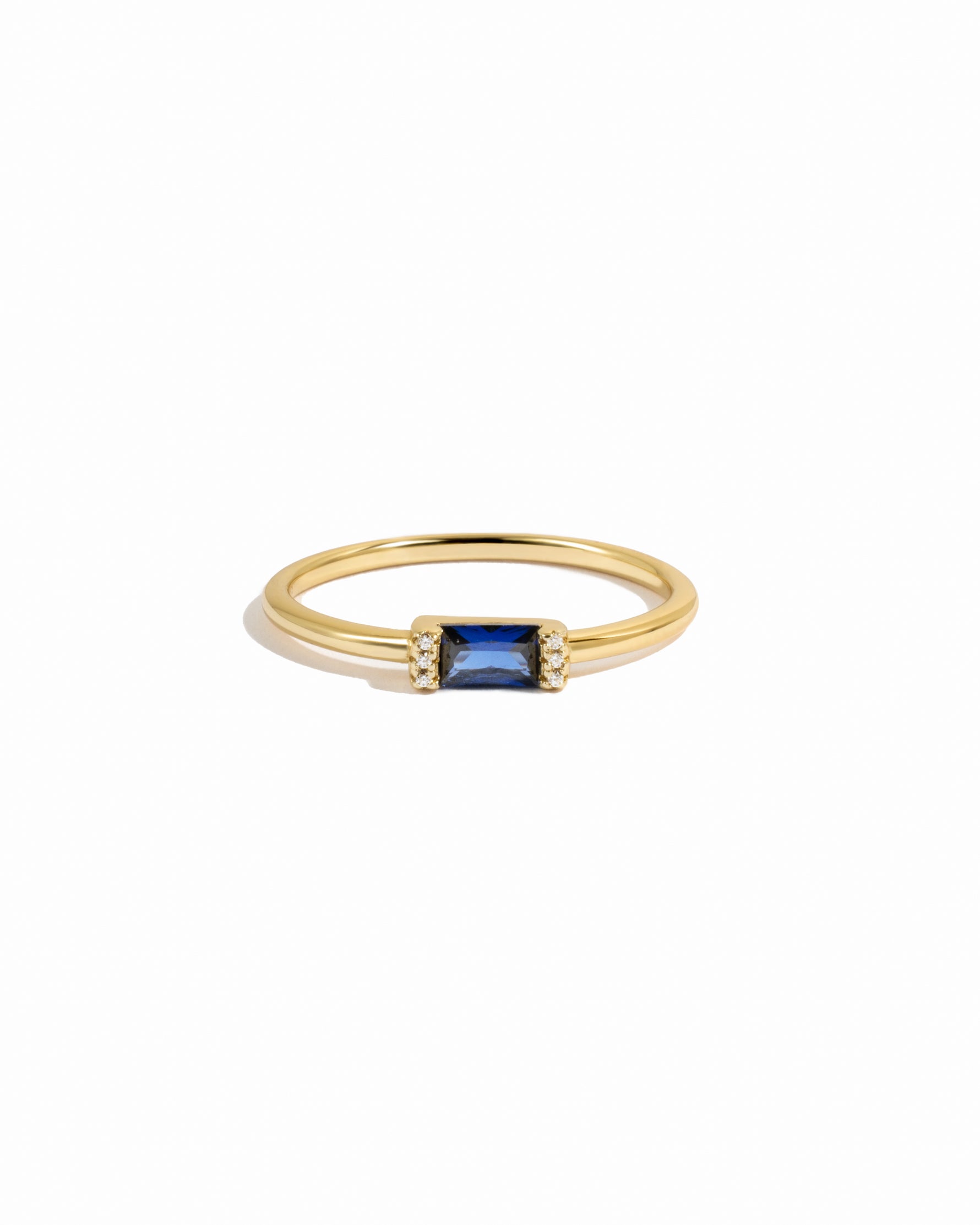 Gold ring with a sapphire gemstone on a white background