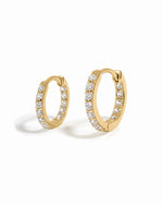 Gold hoop earrings with embedded cubic zirconia diamonds on a white background