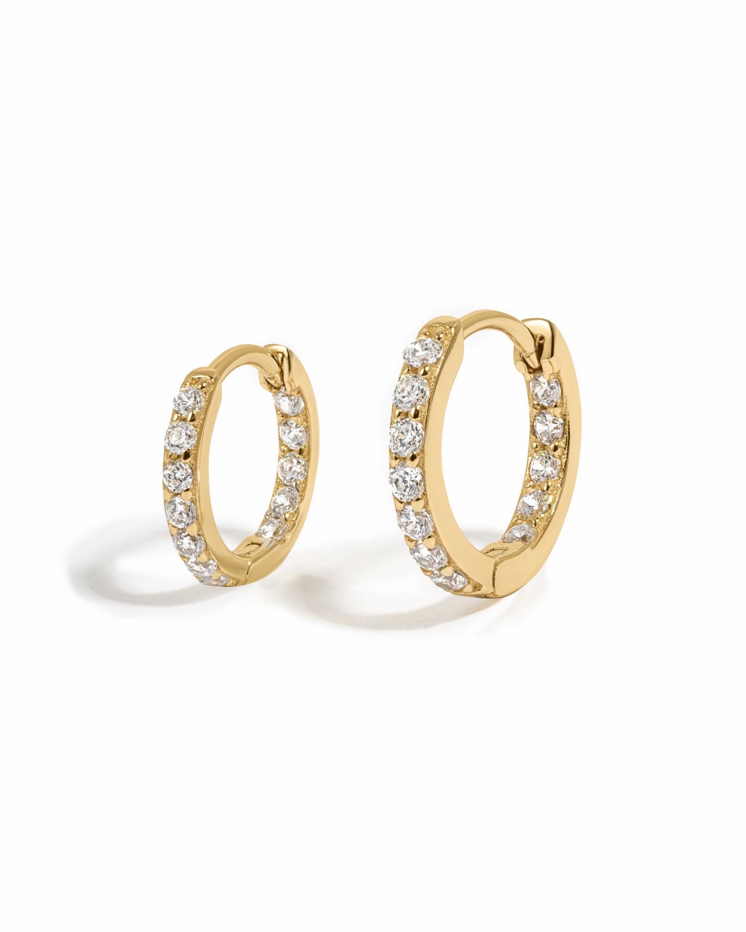 Gold hoop earrings with embedded cubic zirconia diamonds on a white background