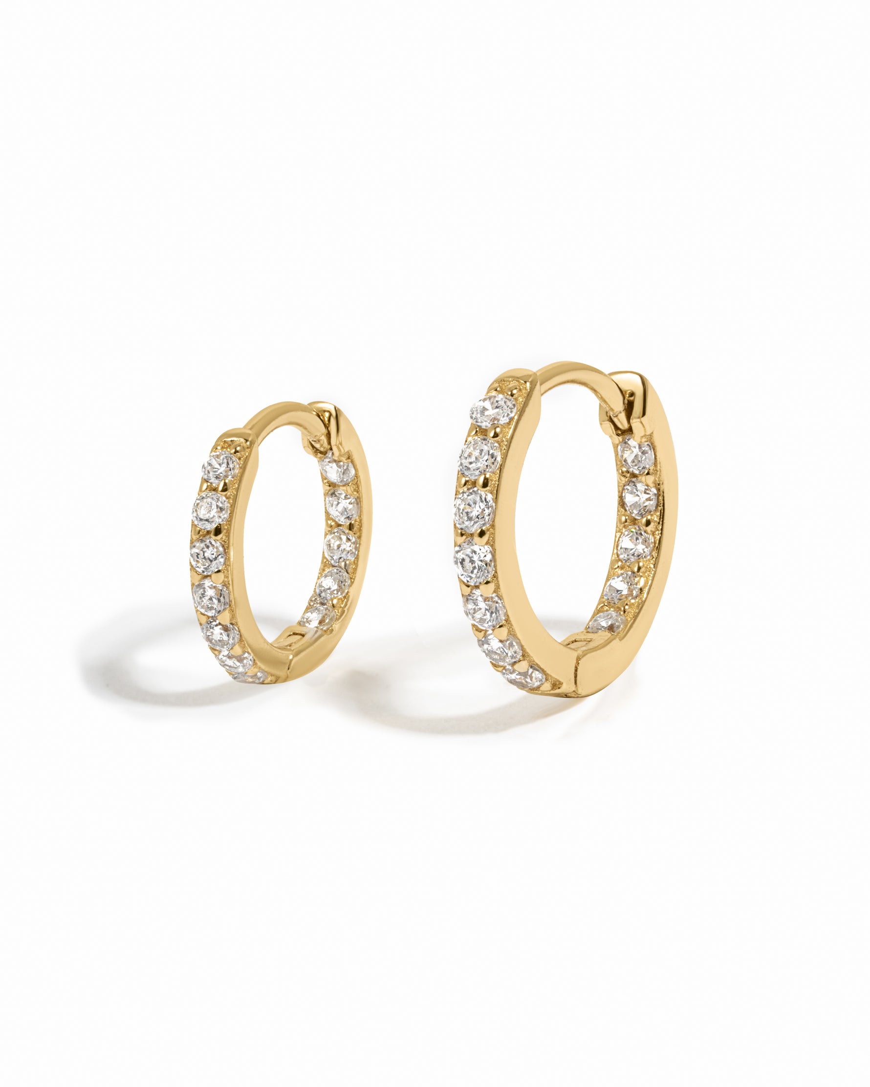 Gold hoop earrings with embedded cubic zirconia diamonds on a white background