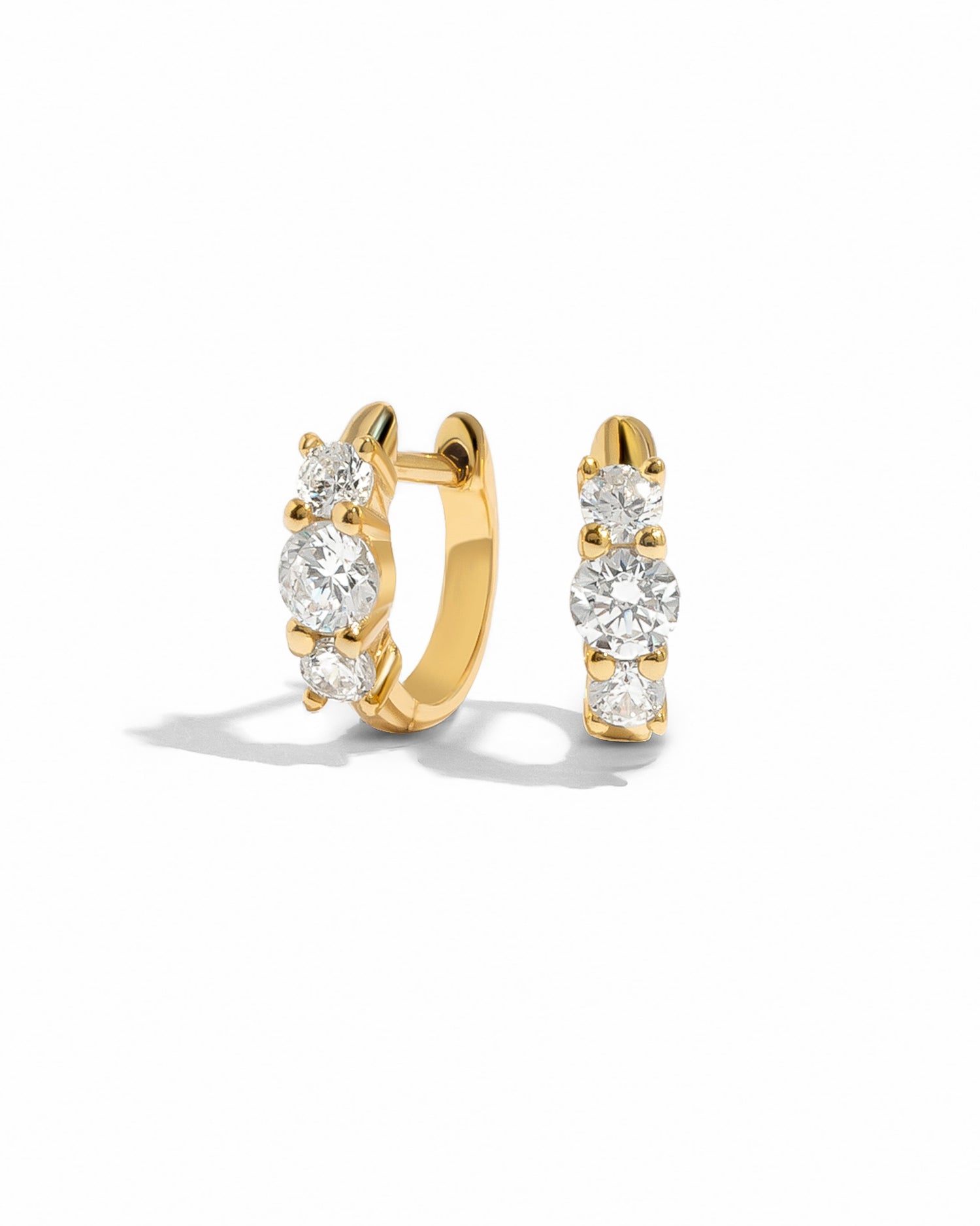 Gold hoop earrings with round white cz gemstones on a white background