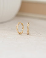 Mini gold hoops featuring a twisted hoop earring design 