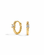 Gold spiral huggie hoop earrings with a small diamond on a white background