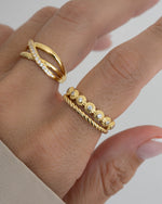 Closeup image of model wearing a diamond ring with a vintage ring design, paired with a textured rope band ring, and a double band statement ring
