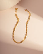 Gold minimalist bracelet set with a beaded bracelet design on a pink background