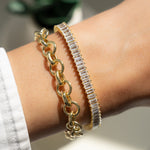 Model wearing gold bracelet stack showcasing a chunky bracelet and a baguette tennis bracelet