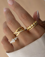 closeup image gold double band stackable ring with cubic zirconia diamonds going across, a bezeled stacking ring, a rope ring, and a oval diamond stacking ring